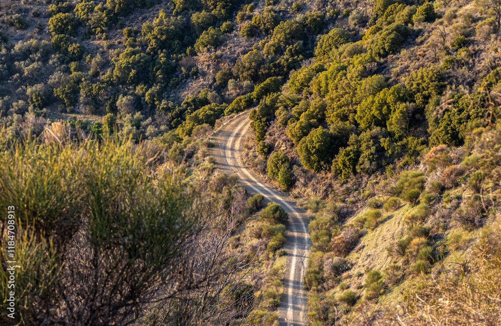 Curved dirt road in the mountains. View from above to a waving off road route on the hills.
