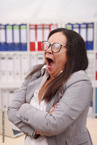 female secretary with glasses and blazer yawns terribly with her mouth open photo