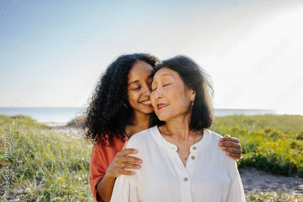 Daughter embracing senior mother on sunny beach day Daughter embracing senior mother on sunny beach day