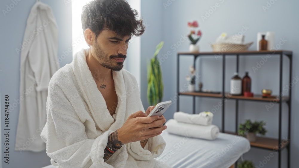 Young man relaxing in a spa room wearing a bathrobe and using a smartphone, surrounded by wellness products and cozy decor, creating a serene and contemporary atmosphere Young man relaxing in a spa room wearing a bathrobe and using a smartphone, surrounded by wellness products and cozy decor, creating a serene and contemporary atmosphere