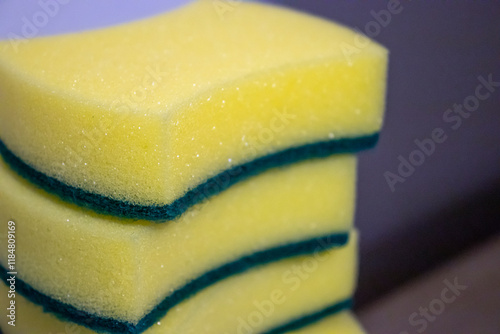 Close-up of stacked kitchen sponges in yellow and green colors, perfect for household cleaning tasks and dishwashing. photo