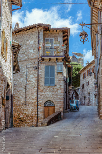 Obraz na płótnie Medieval architecture and narrow streets of Assisi, traditional stone houses with balconies and a charming vintage scooter hidden in the distance. w salonie