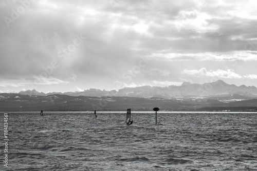 Schwarz weiß Aufnahme von windsurfer auf dem Bodensee, vor Bergkulisse. photo