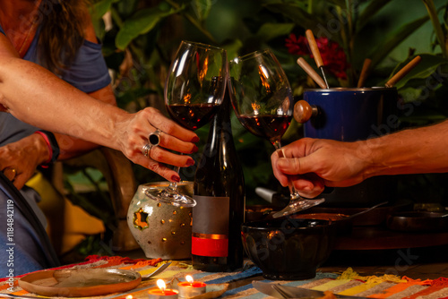 Brinde com taças de vinho em jantar intimista com fondue e decoração aconchegante photo