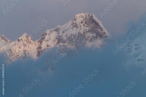 Snow  and clouds covered mountain peak, in winter season photo