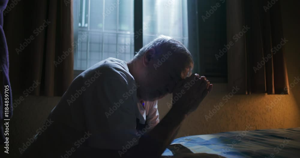 Elderly man sitting on bed with hands clasped in prayer seeking divine guidance and support reflective moment of faith hope and introspection in solitude