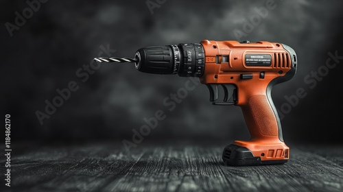 Orange cordless drill with bit on dark wood. photo