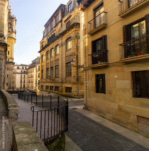 Narrow alley with traditional buildings, balconies, and street lamps in the old town of San Sebastian, Spain. Urban architecture. photo