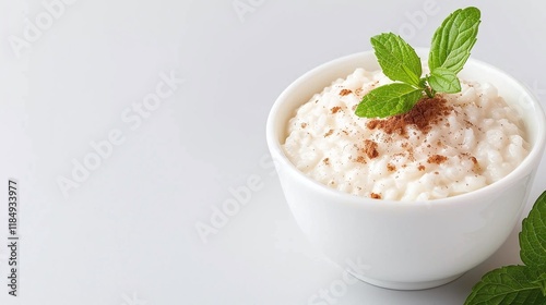 Rice pudding on white, cinnamon and mint garnish, creamy rice dessert, dessert close up copy space, minimalist food


 photo