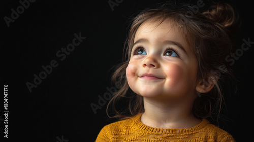 Child smiling with admiration while wearing a cozy yellow sweater indoors during evening hours photo