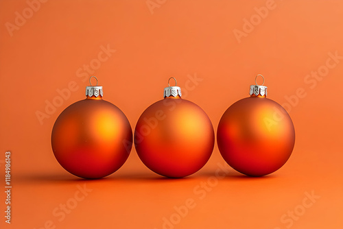 Three orange holiday ornaments placed on a matching orange background for a vibrant seasonal design