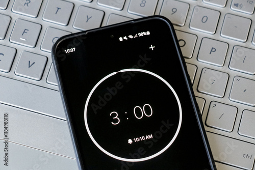 A phone with a black and white 3-minute timer to study with pomodoro method on laptop keyboard, study business background
