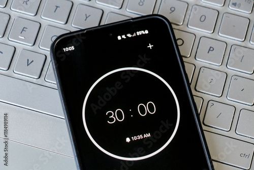 A phone with a black and white 30-minute timer to study with pomodoro method on laptop keyboard, study business background