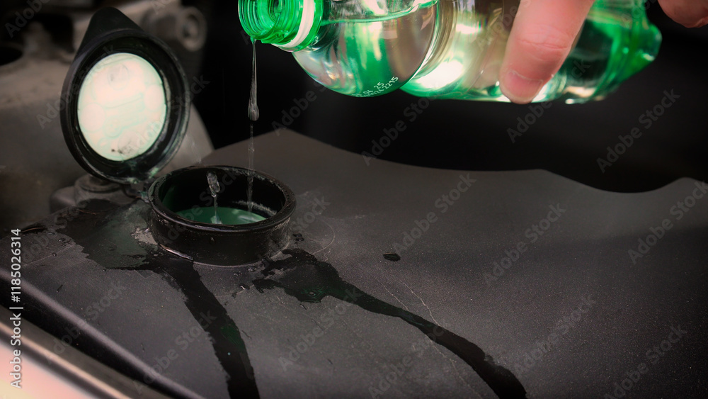 Mechanic pouring windshield washer fluid into car reservoir