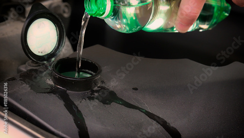 Mechanic pouring liquid into car reservoir tank