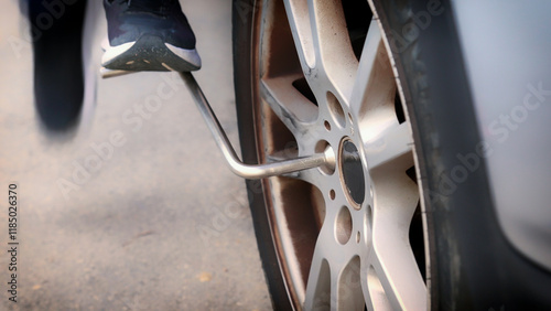 Mechanic changing car tire using wrench and foot pressure