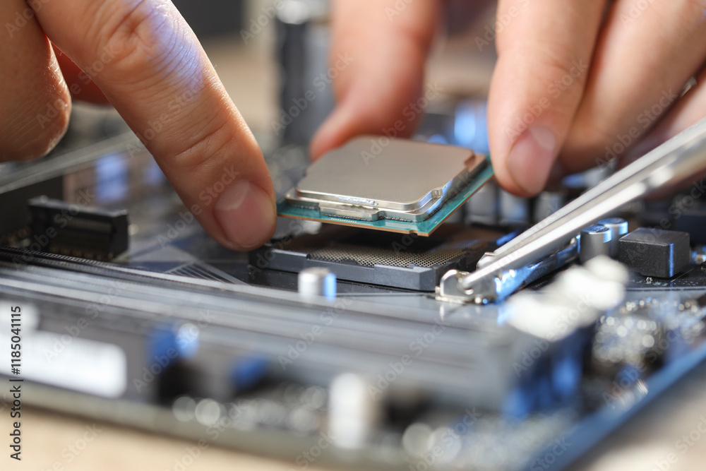 Man installing computer chip onto motherboard at table, closeup