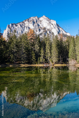 Lake Kreuzteich surrounded by mountain peak Pribitz in Hochschwab Alps in Tragoess, Styria, Austria. Forest in vibrant autumn foliage. Crystal-clear water reflects majestic ridges. Mirror-like effect photo