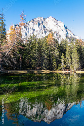 Lake Kreuzteich surrounded by mountain peak Pribitz in Hochschwab Alps in Tragoess, Styria, Austria. Forest in vibrant autumn foliage. Crystal-clear water reflects majestic ridges. Mirror-like effect photo