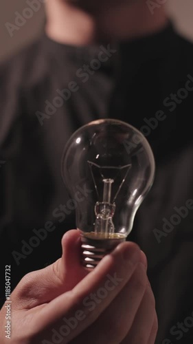 Vertical Video : Man holding a light bulb and it turns on, concept of idea