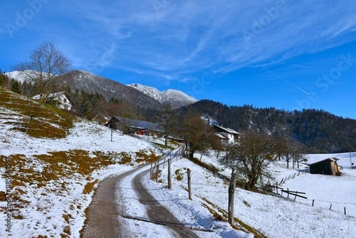 Gravel road and Bašelj village with mountain above in Gorenjska, Slovenia in winter photo