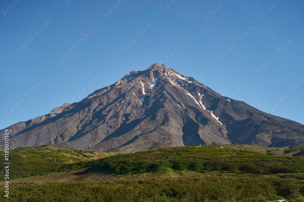Fototapeta premium Koryaksky volcano. This is a truly stunning view of a magnificent volcano, surrounded by rugged terrain and clear blue skies