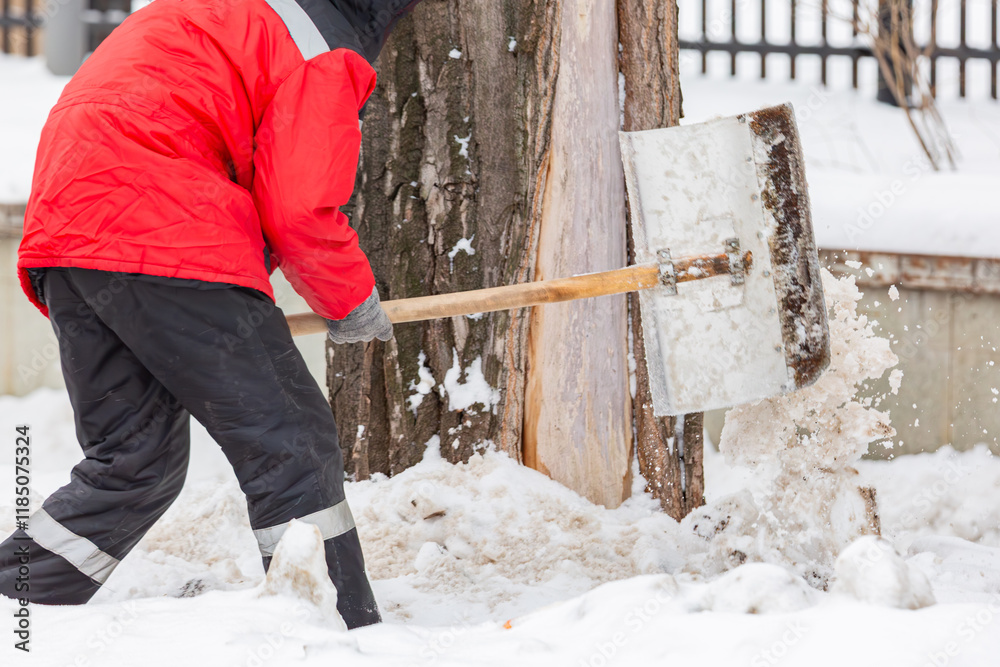 Communal services worker cleans snow with shovel from road in winter. Cleaning city streets and roads after snow storm in Moscow, Russia. Communal services worker cleans snow with shovel from road in winter. Cleaning city streets and roads after snow storm in Moscow, Russia.