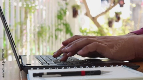 Close up of hand typing password on the computer laptop keyboard, on wooden desk.
