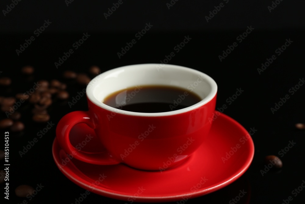 Red cup with coffee and roasted beans on black background, closeup Red cup with coffee and roasted beans on black background, closeup