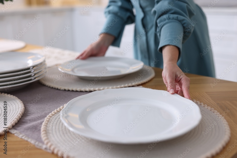 Woman setting table for dinner at home, closeup Woman setting table for dinner at home, closeup