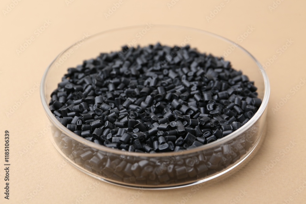 Black plastic granules in petri dish on beige background, closeup Black plastic granules in petri dish on beige background, closeup
