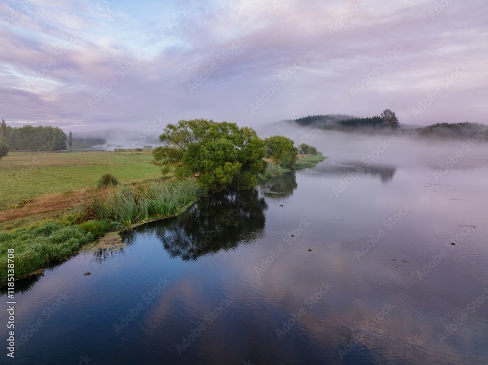 Obraz premium Misty morning on a tranquil lake. Ducks rest on the still water, reflecting the sky. Peaceful rural scene. LAKE ANIWHENUA, MURUPARA, BAY OF PLENTY, NEW ZEALAND
