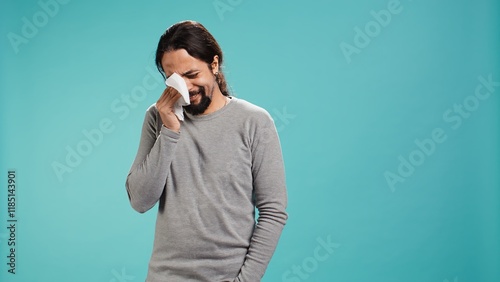 Portrait of troubled man weeping feeling saddened and rattled by events, isolated over studio backdrop. Person crying, wiping tears with handkerchief, left speechless by troubling news, camera B photo