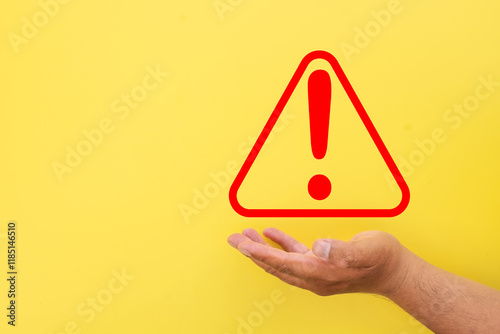 Red warning attention sign holding by hand concept for alert messages, danger symbols, important notifications, suitable for safety.