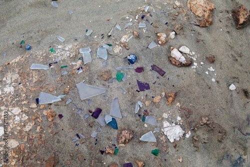 Broken glass litter the sand, a testament to discarded waste. Environmental pollution. POUTO PENINSULA, POUTO, NORTHLAND, NEW ZEALAND photo