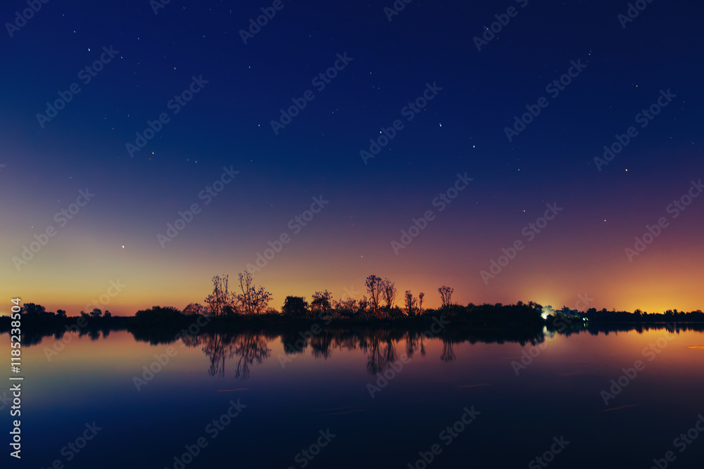 Φωτογραφία Beautiful and colorful sunset reflecting on calm lake water with starry sky and