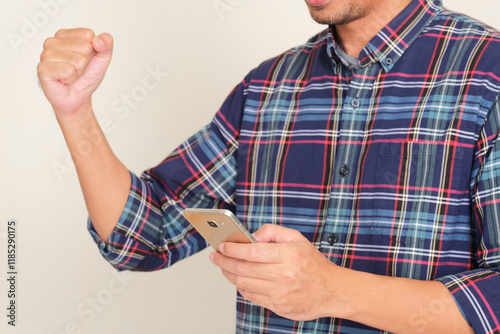 A man clenched fist showing success gesture while holding mobile phone photo