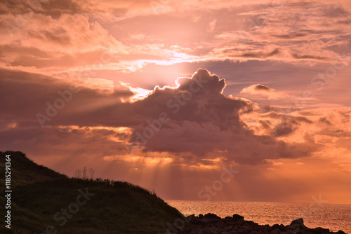 A stunning sunset casting beautiful warm hues over ocean waves, graciously highlighted by evocative cloud formations photo