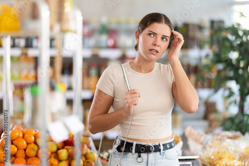 Young woman buyer forgot what she wanted to buy at grocery store
