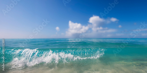 Fototapeta Naklejka Na Ścianę i Meble -  Close up of a wave crashing on a tropical beach with clouds diffused in the distance 