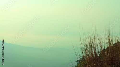 Landscape background of sky, cloud, mist, mountain and grass in the foreground. 4K 3840x2160, wide and tilt up shot. Can be establishing shot. Time lapse.