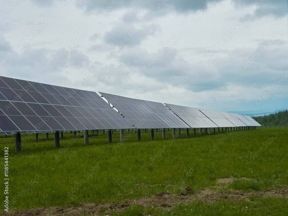 Solar panels in a field under a cloudy sky. Clean energy, renewable resource, sustainable power.