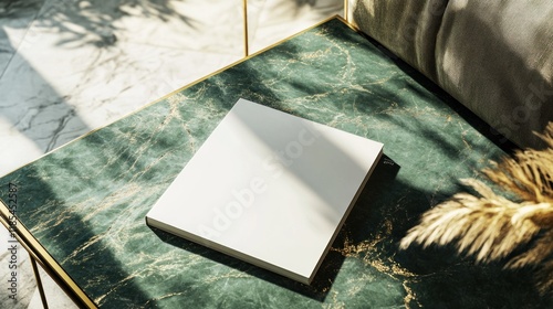 Blank square book mockup on green marble table.