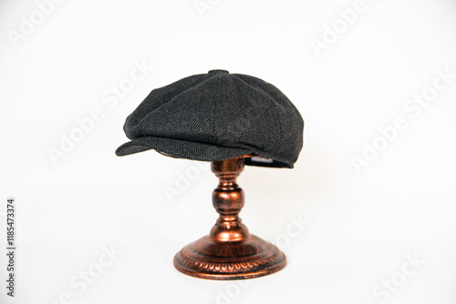 Detail of a black herringbone newsboy hat mounted on a bronze mannequin head on a white background. concept photo of a classic newsboy hat in jet black on a bronze mannequin