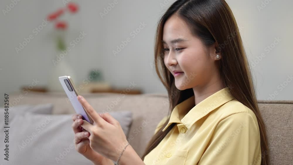 A young woman relaxes on a cozy couch, smiling as she browses her smartphone in a modern living room A young woman relaxes on a cozy couch, smiling as she browses her smartphone in a modern living room
