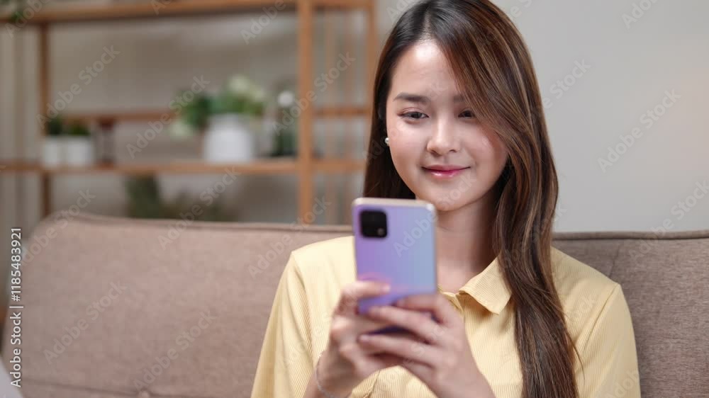 A young woman relaxes on a cozy couch, smiling as she browses her smartphone in a modern living room A young woman relaxes on a cozy couch, smiling as she browses her smartphone in a modern living room