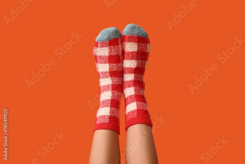 Legs of young woman in warm checkered socks on orange background photo