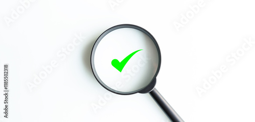A magnifying glass is used to look at a green check mark. The check mark is on a white background