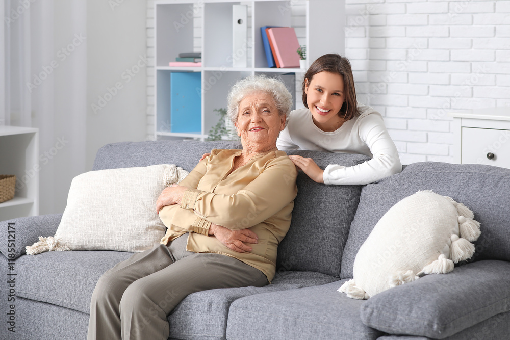 Obraz premium Smiling nurse hugging senior woman on sofa at home