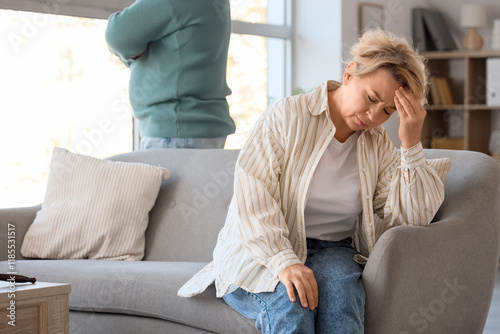 Foto Upset mature woman sitting on sofa and her husband at divorce lawyer's office